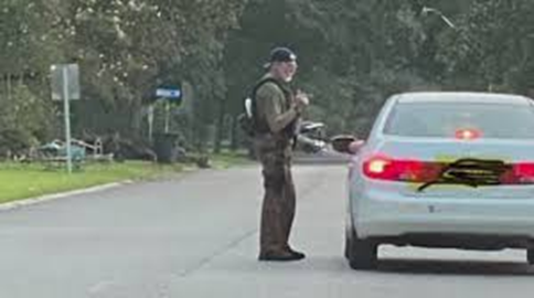 Photo shows military speaking with a person in a white vehicle in the road.