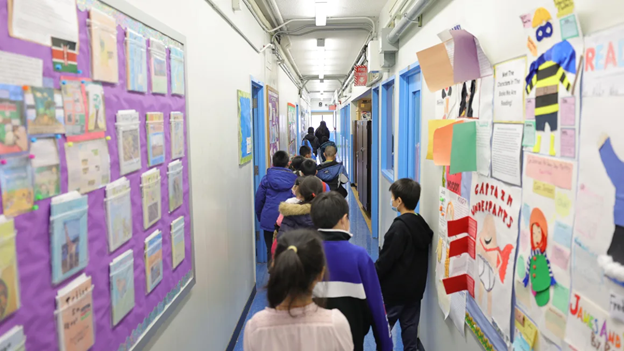 photo showing backs of students who are waiting in line in a school hallway.