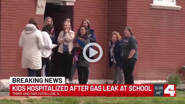Kids hospitalized after gas leak at school. Photo of students and adults outside of school. 