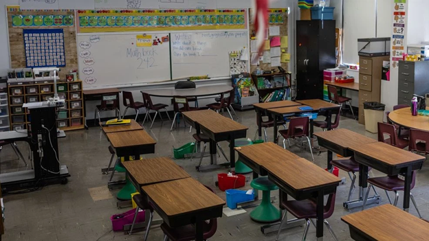 This is a photo of an empty classroom with colorful chairs and a whiteboard with random writing.