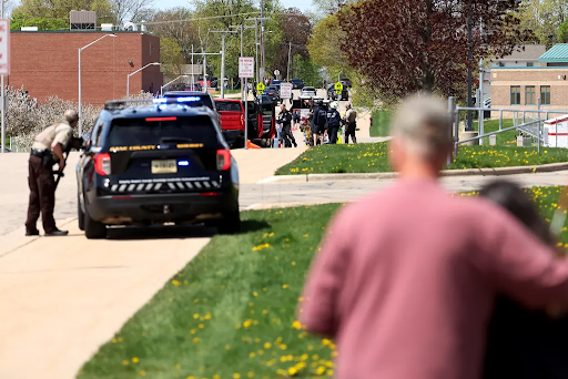 man hugging child with police car in distance