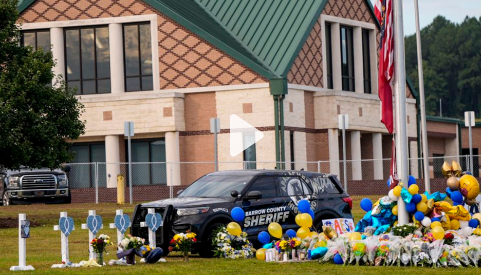 The picture shows a memorial outside of Apalachee High School with a Sheriff SUV parked behind the memorial.
