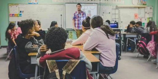 teens in a classroom with male teacher in front of white board