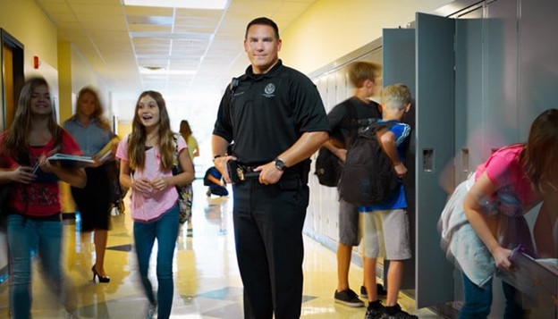 photo of school resource officer and students in a school hallway.